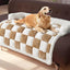 Golden retriever on plush checkered dog mat in white and brown on a sofa.