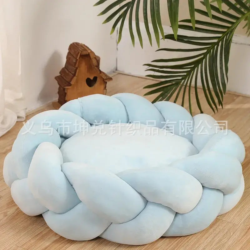 Cozy blue handmade knit pet bed in a cozy room setting with plants and wooden decor.