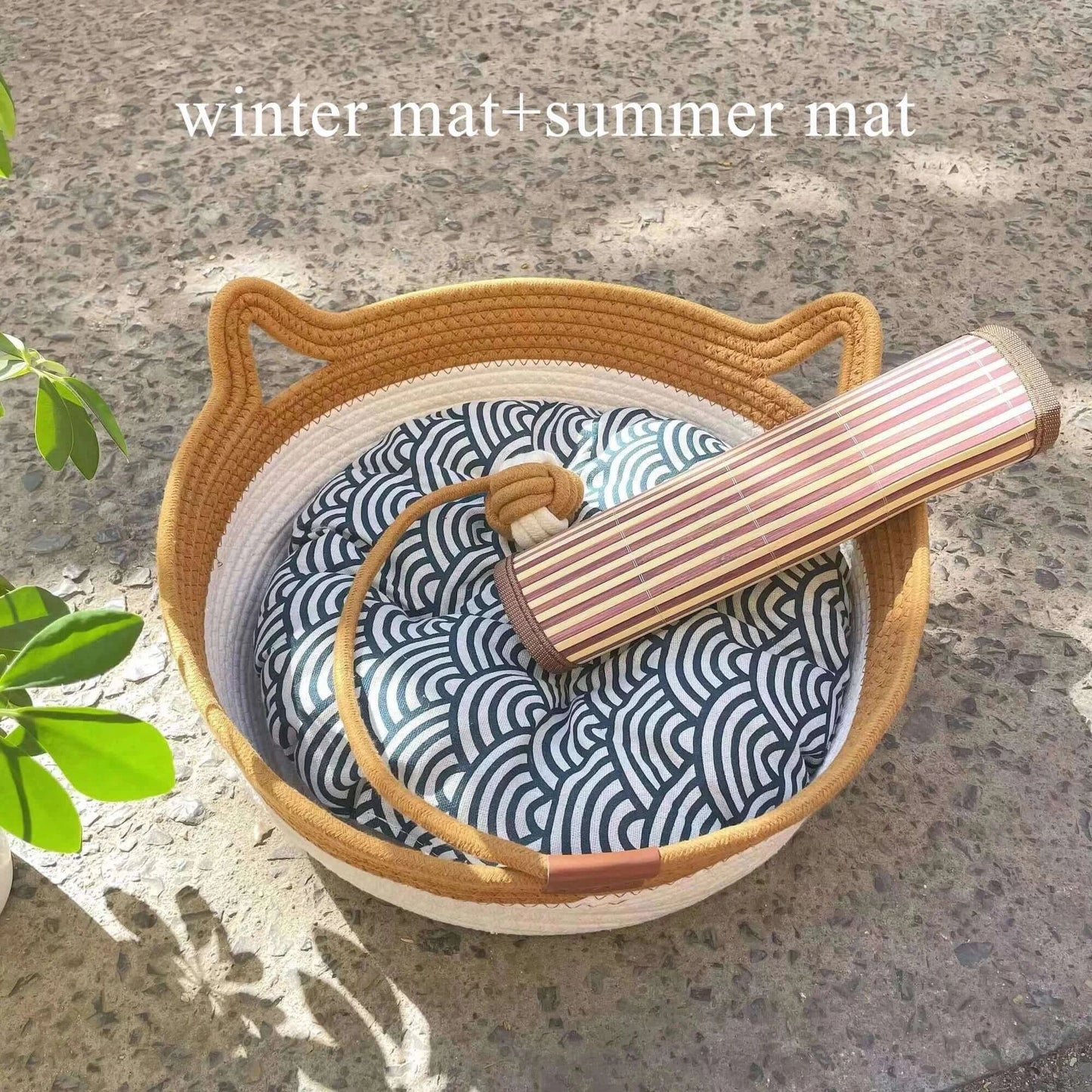 Natural rattan cat bed with patterned cushion and summer mat on a textured stone surface.