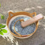 Natural rattan cat bed with washable basket and patterned cushion, placed outdoors on a stone surface.