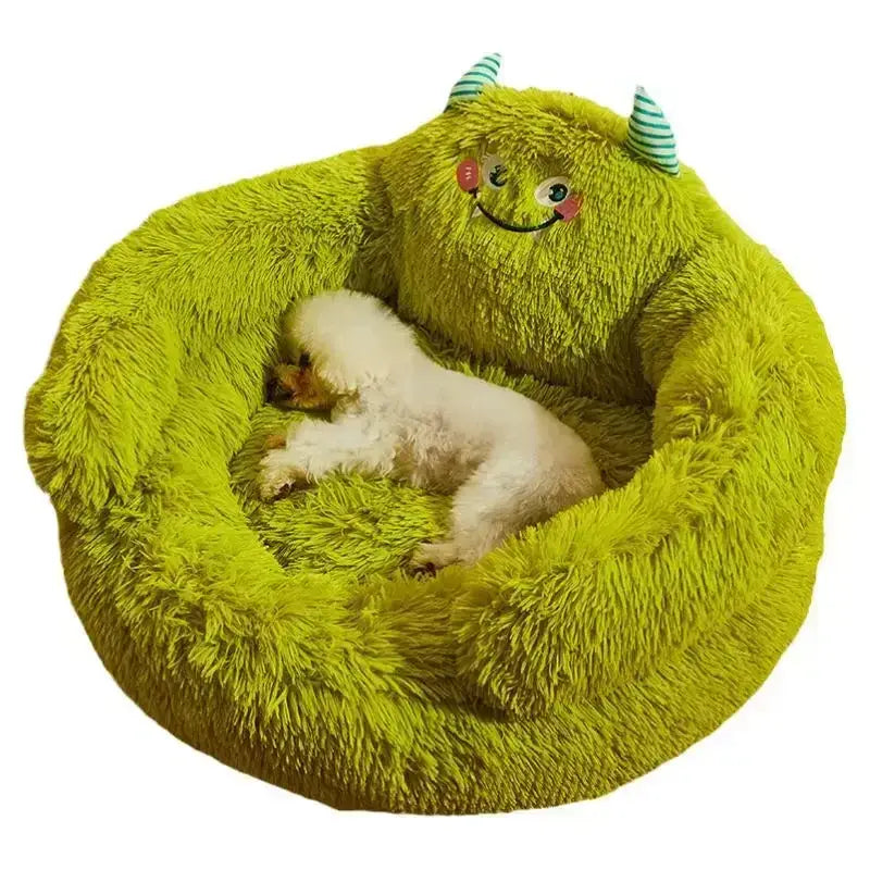 Small dog sleeping on a green plush round pet bed with a cute monster design.