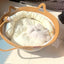 Cozy white cat lounging in a natural rattan cat bed with washable basket in sunlight.