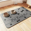 Splash-proof pet feeding mat with paw prints and bone designs, holding two bowls on wooden floor.