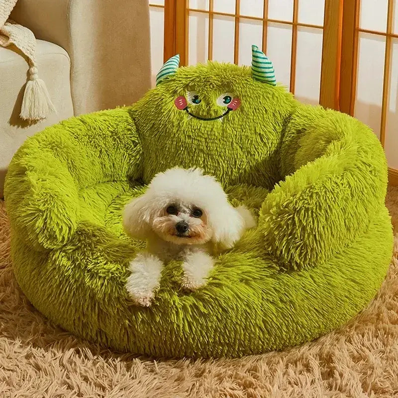 Small white dog resting on a plush green monster-themed pet bed in a cozy home setting.