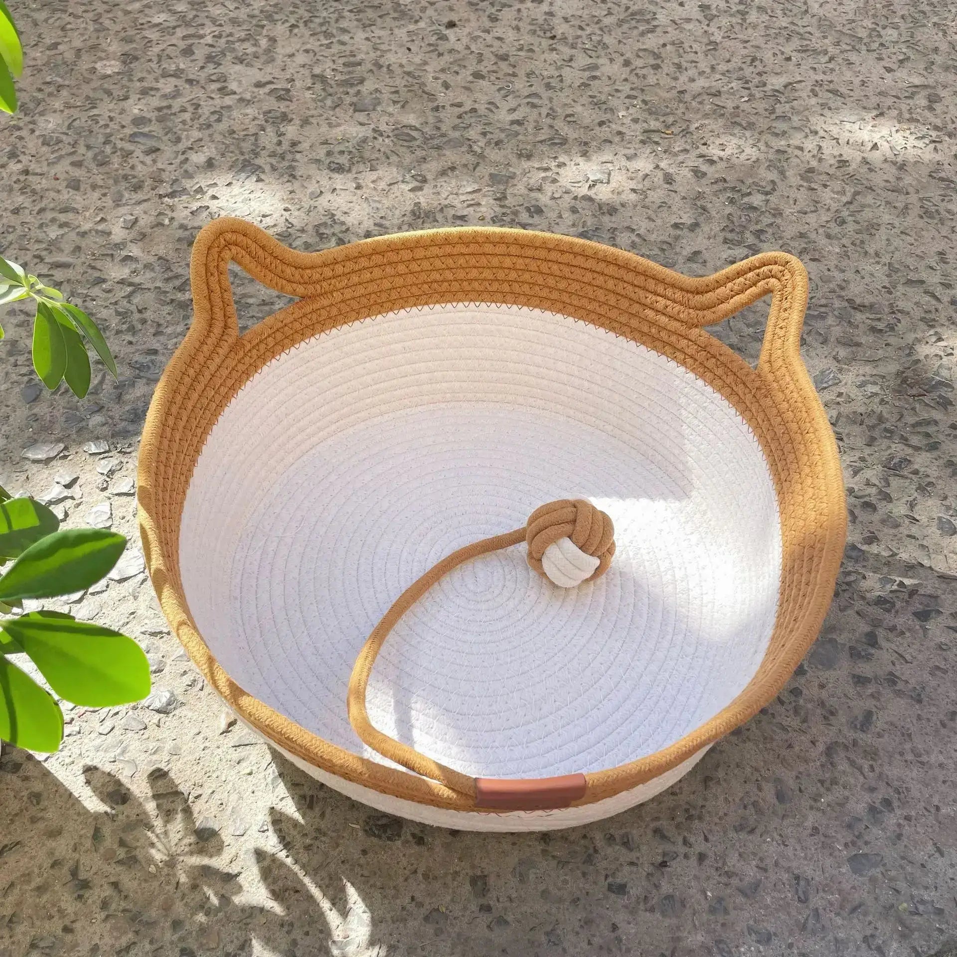 Natural rattan cat bed with a washable basket, featuring a durable design and cozy space for cats, in sunny outdoor setting.