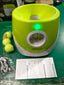 Automatic dog tennis ball launcher with balls and instructions on green background