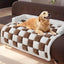 Golden retriever lying on a plush, thickened dog mat with a checkered design, placed on a brown couch.