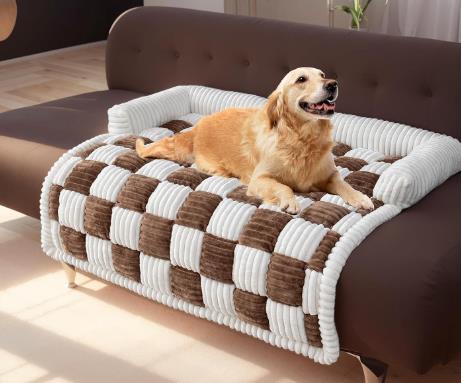 Golden retriever lying on a plush, thickened dog mat with a checkered design, placed on a brown couch.